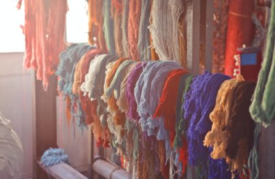 various colorful threads hanging on rail in workshop