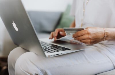 person using a macbook and holding a credit card